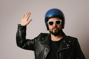 Handsome biker men raised palm for greeting, wears leather jacket and helmet.