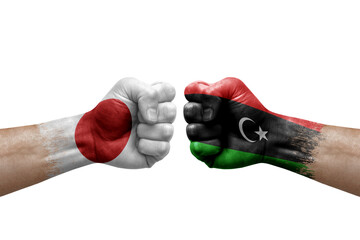 Two hands punch to each others on white background. Country flags painted fists, conflict crisis concept between japan and libya