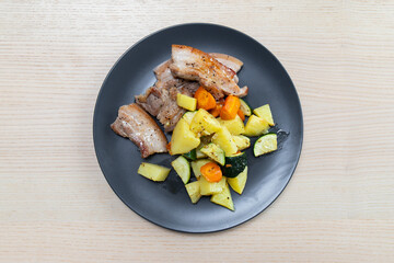 A plate of pork belly steak with roasted vegetables.