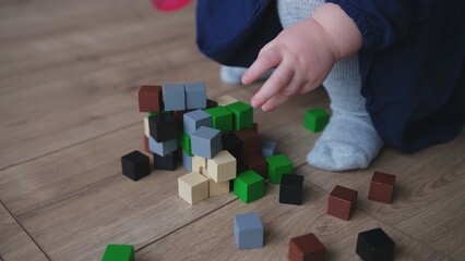 Little Caucasian Baby Girl Crushing and Destroying Tower Toy Made of Wooden Blocks Creating Mess in the Living Room in Split Second	
