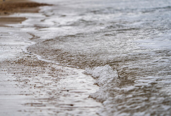 Fototapeta na wymiar Low tide waves breaking against sandy beach