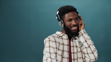 An african young man in a white shirt is listening to music and dancing