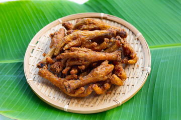 Fried chicken feet in bamboo basket on banana leaf