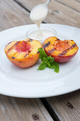 Still life of grilled peaches set on a white plate with cream