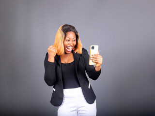 young black excited businesswoman holding mobile phone celebrating after ben promoted on her job