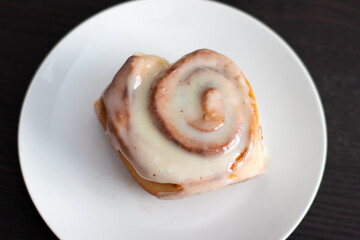 single cinnamon roll on a round white plate in the kitchen