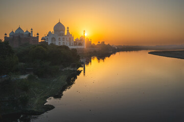 Fototapeta premium A wide angled view of Taj Mahal in Agra captured with Yamuna River beside. Taj Mahal during sunset in agra.