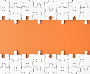 white paper jigsaw puzzle on orange paper background