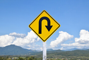 Traffic sign: Right U-turn sign on cement pole beside the rural road with white cloudy bluesky background, copy space.