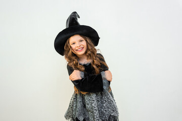 Surprised young witch on a white background. The costume of the sorceress for the carnival. A magician's hat on a little girl. A beautiful costume for magic.