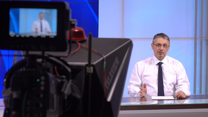 News anchor in the studio, live. A charismatic white man discussing daily events .