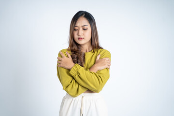 young woman feeling cold with both hands hugging her arms