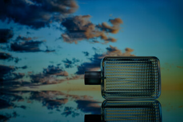 close-up view of perfume bottle on sunset sky background