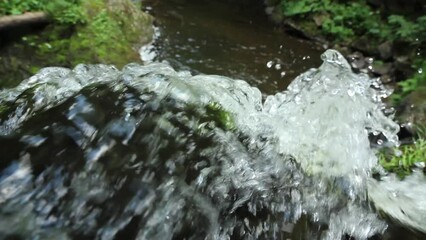 View of rushing water through green moss