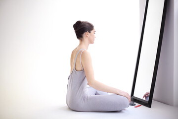 Mentally preparing for her performance. Young ballerina sitting in front of a mirror and looking at...