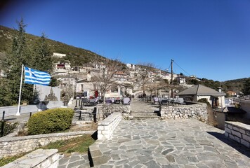 igiades village on the mountain mitsikeli, greek fllag waving old traditional houses in ioannina