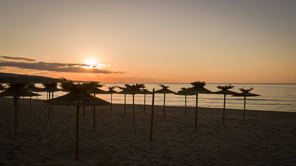 Fototapeta na wymiar Beach umbrella on the beach with beautiful sunrise