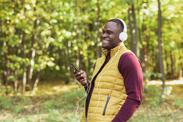 African american man listens music in spring park copy space and place for advertising. Gadget, app and streaming service concept