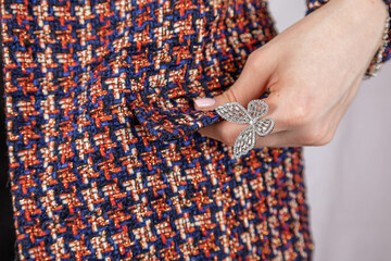 Close-up of woman's hand on tweed jacket holding flower. High quality photo