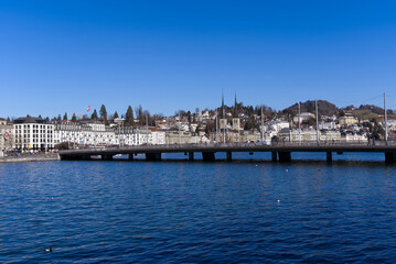 Fototapeta na wymiar Cityscape of Luzern with Lake Bridge and lake Lucerne in the foreground on a sunny winter day. Photo taken February 9th, 2022, Lucerne, Switzerland.
