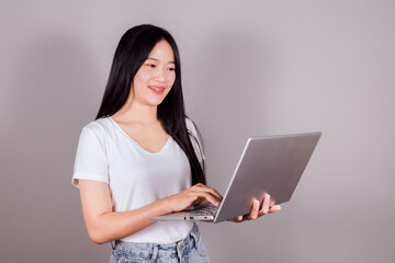Portrait of happy young asian girl using laptop computer on gray background