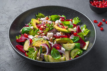 Vitamin salad with vegetables, feta, nuts and pomegranate close-up. Beetroot salad with avocado, beetroot and cucumber. Cleansing, antioxidant-rich food.