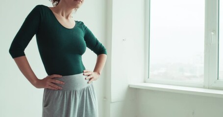 Fitness class. Morning workout. Active lifestyle. Athletic woman warming up stretching shoulder muscles before training in light studio interior.