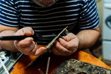 Hands solder electronics chip. Finely handmade. Soldering iron in hand.