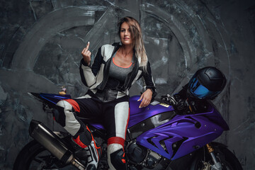 Fototapeta na wymiar Bold woman biker dressed in protective suit against dark background