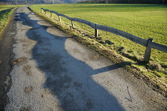 Zaun mit Schattenwurf, Licht und Schatten in einer ländlichen Gegend auf einem Weg oder einer Straße