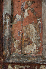 Detail of textured, old, weathered wooden door with peeling and cracked varied colored paints.