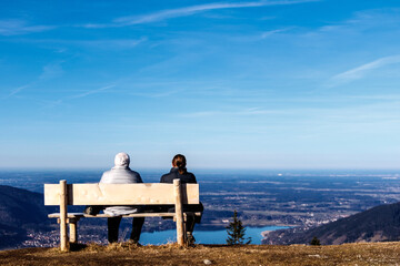 Two people on a bench on a mountain lookout