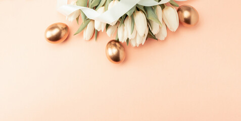 Golden eggs with spring white tulips on pastel pink background in Happy Easter decoration. Foil...