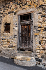Fototapeta na wymiar Vieille porte et fenêtre sur la façade d'une maison abandonnée dans un petit village du puy de dôme avec un mur de vieilles pierres ocre
