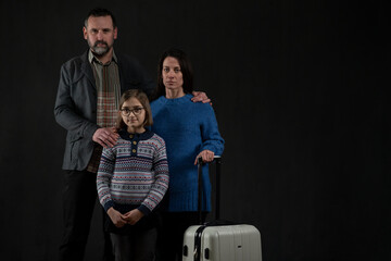 Refugee family with one child looking at camera on black background, Ukraine war concept. - obrazy, fototapety, plakaty