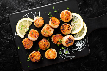 Grilled scallops with creamy lemon spicy sauce on black background. top view