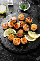 Grilled scallops with creamy lemon spicy sauce on black background.