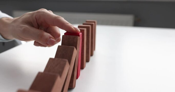 Person stops falling blocks on table closeup