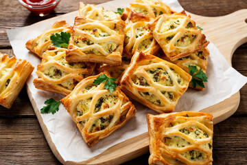 Puff pastry squares filled with feta cheese and spinach on wooden table.