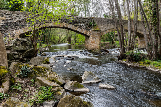 Vieux pont romain enjambant la rivière Couze au pied du village de Neschers sur un chemin de randonnée
