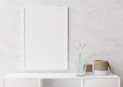 Empty vertical picture frame on white wall in modern living room. Mock up interior in minimalist, scandinavian style. Free space for picture. Console, rattan basket, dried grass in vase. 3D rendering.