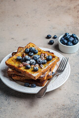 French toast with blueberries, pecan and maple syrup for breakfast on white plate.