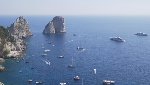 Aerial view of the Faraglioni rocks in the sea near the Capri island, Italy. A lot of ships berthed near the coast.