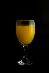 a glass of orange juice on black background