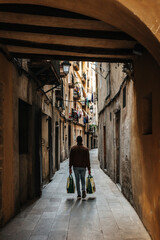 Man carrying home groceries in a small side street in Barcelona, Spain