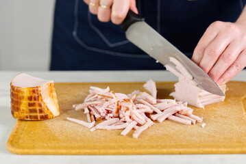 a woman's hand cuts a juicy piece of ham into pieces. wife cooks delicious breakfast. close up