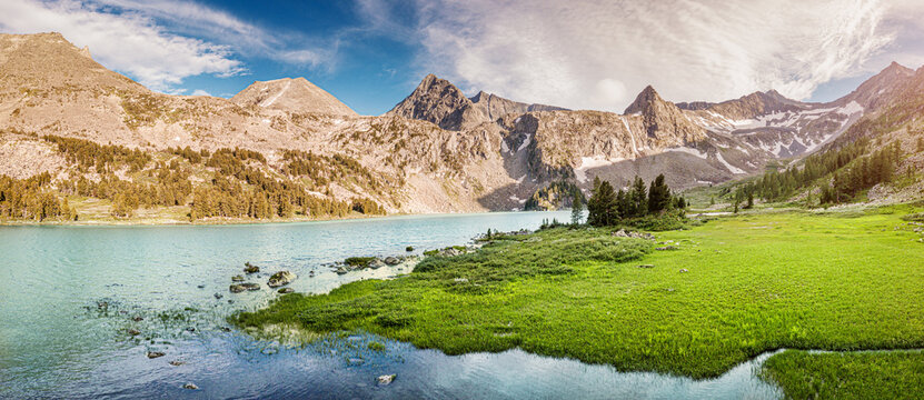 Panoramic aerial view of famous natural attraction of Altai and Russia - the Krepkoe Lake at sunrise with illuminated mountain peaks. National park and hiking concept