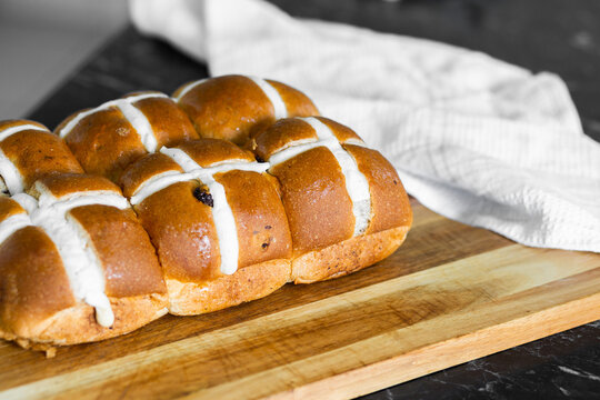 Fresh baked hot cross buns on board on kitchen bench