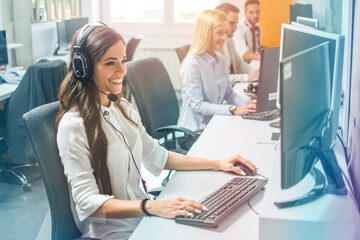 Confident young woman in headset, sitting in office, working as operator of call center or support...