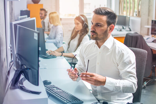 Portrait Of Worried And Confused Businessman Sitting At Desk Using Computer, Taking Off Glasses Looking At Monitor Screen And Squinting.